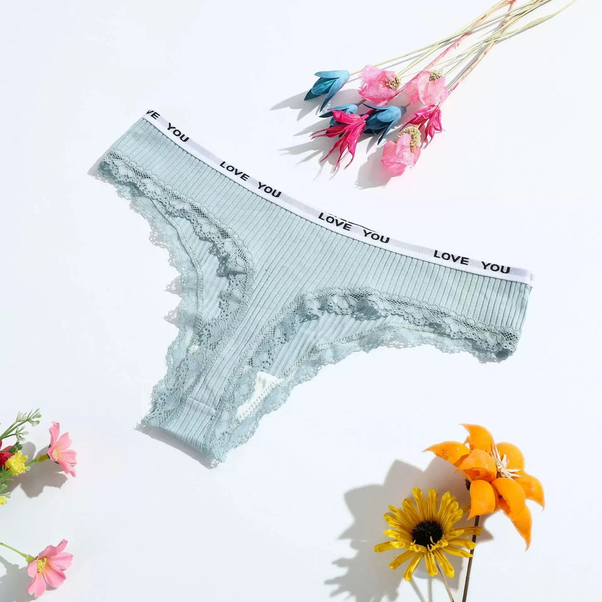 Light blue ribbed lace-trimmed panties featuring a white waistband printed with the text LOVE YOU, laid flat on a white surface surrounded by small artificial flowers.