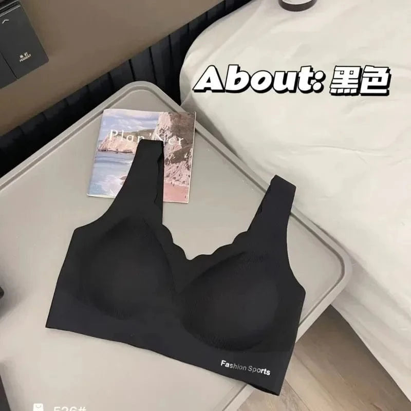 A black wireless sports bra with a scalloped neckline sits on a grey tray next to a notebook on a bed.