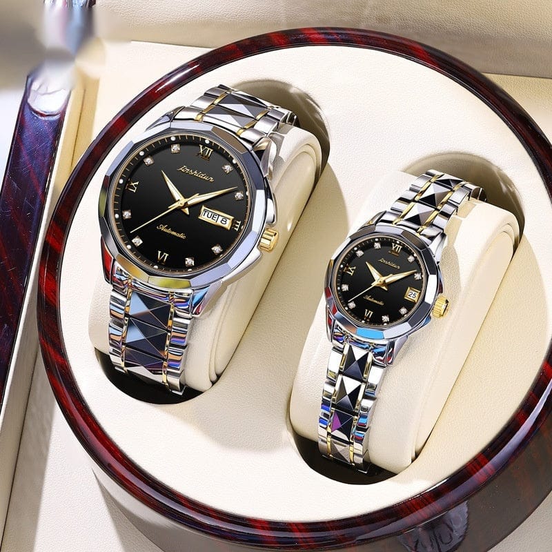 A pair of silver and gold-toned watches with black dials, crystal hour markers, and faceted metallic bands presented in a round, polished wooden display case.