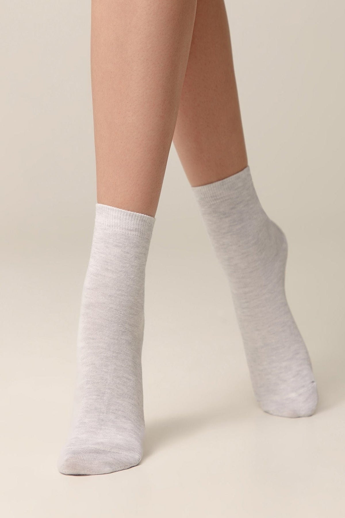 A pair of light grey, mid-calf socks worn on a person's legs against a neutral background.