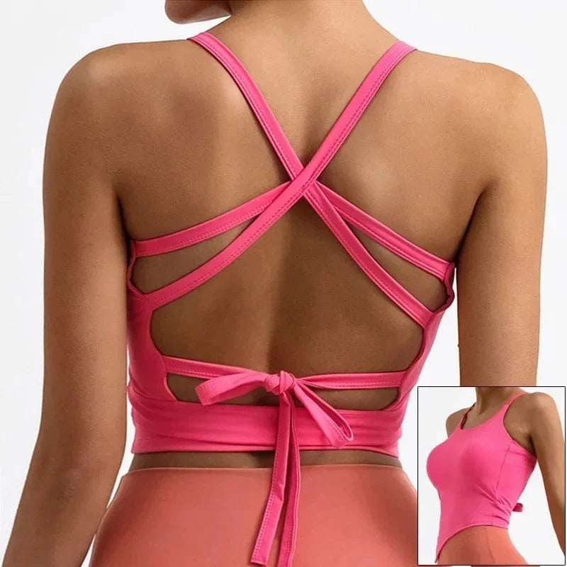 A pink athletic tank top featuring a strappy crisscross back and a tied bow closure, shown from the back with an inset view of the side profile.