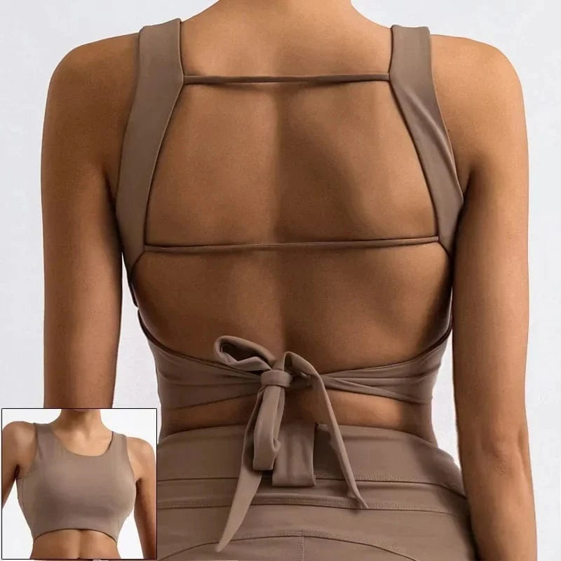 A beige athletic sports bra with a low-cut back featuring two horizontal straps and a tie-closure at the bottom, shown from both the back and front views.