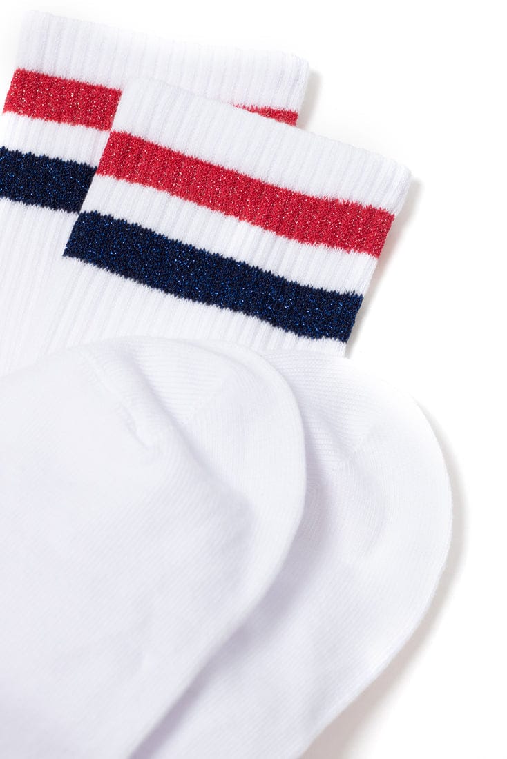 A pair of white ankle socks featuring one red glitter stripe and one blue glitter stripe around the ribbed cuffs.