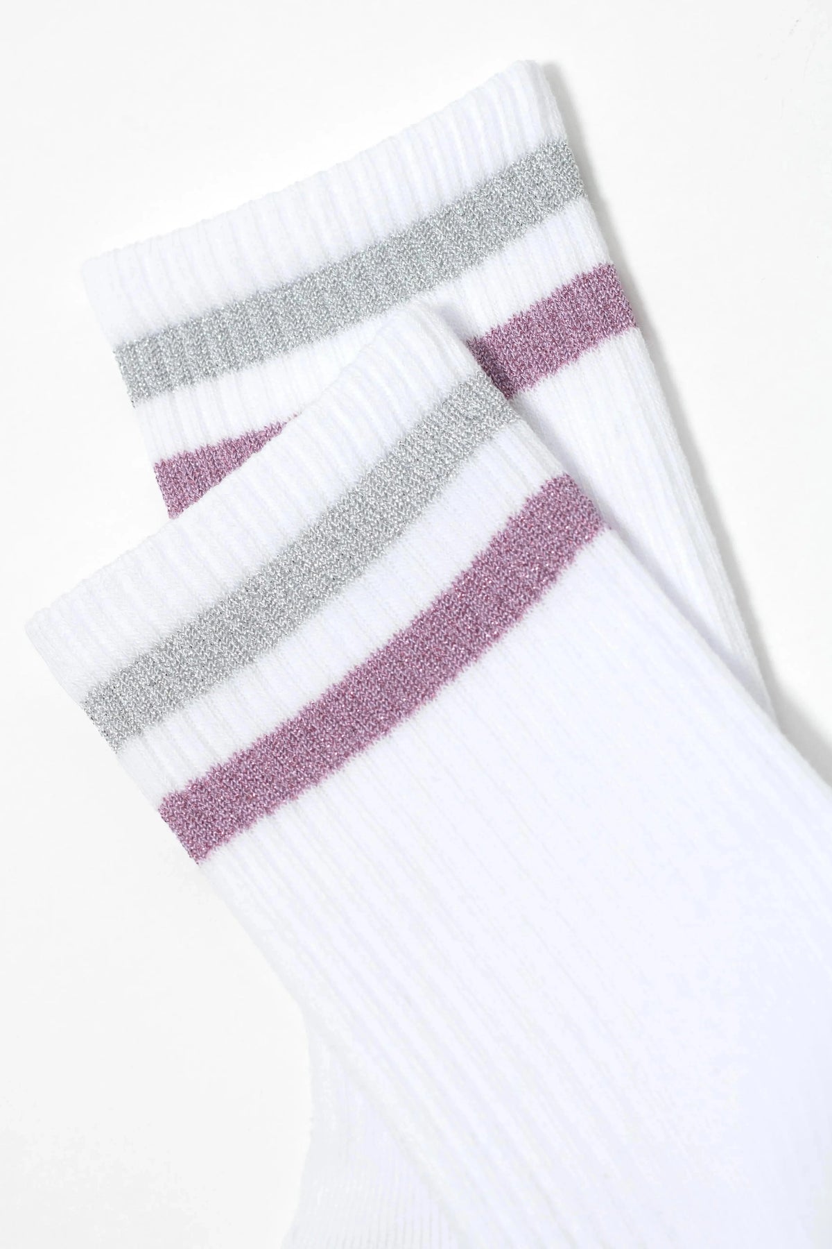 A pair of white ribbed socks featuring two horizontal stripes in silver and mauve near the top cuffs.