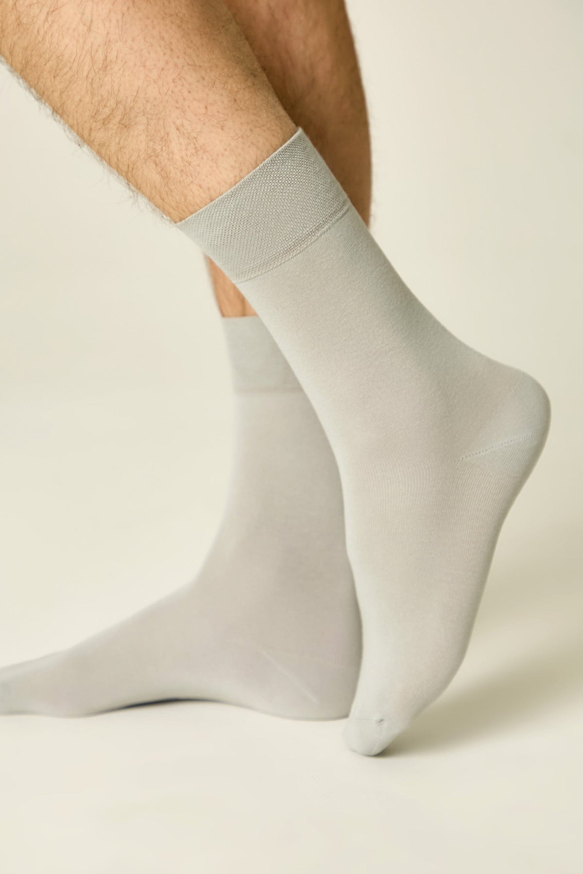 Light grey crew-length socks worn on a person's feet against a plain off-white background.