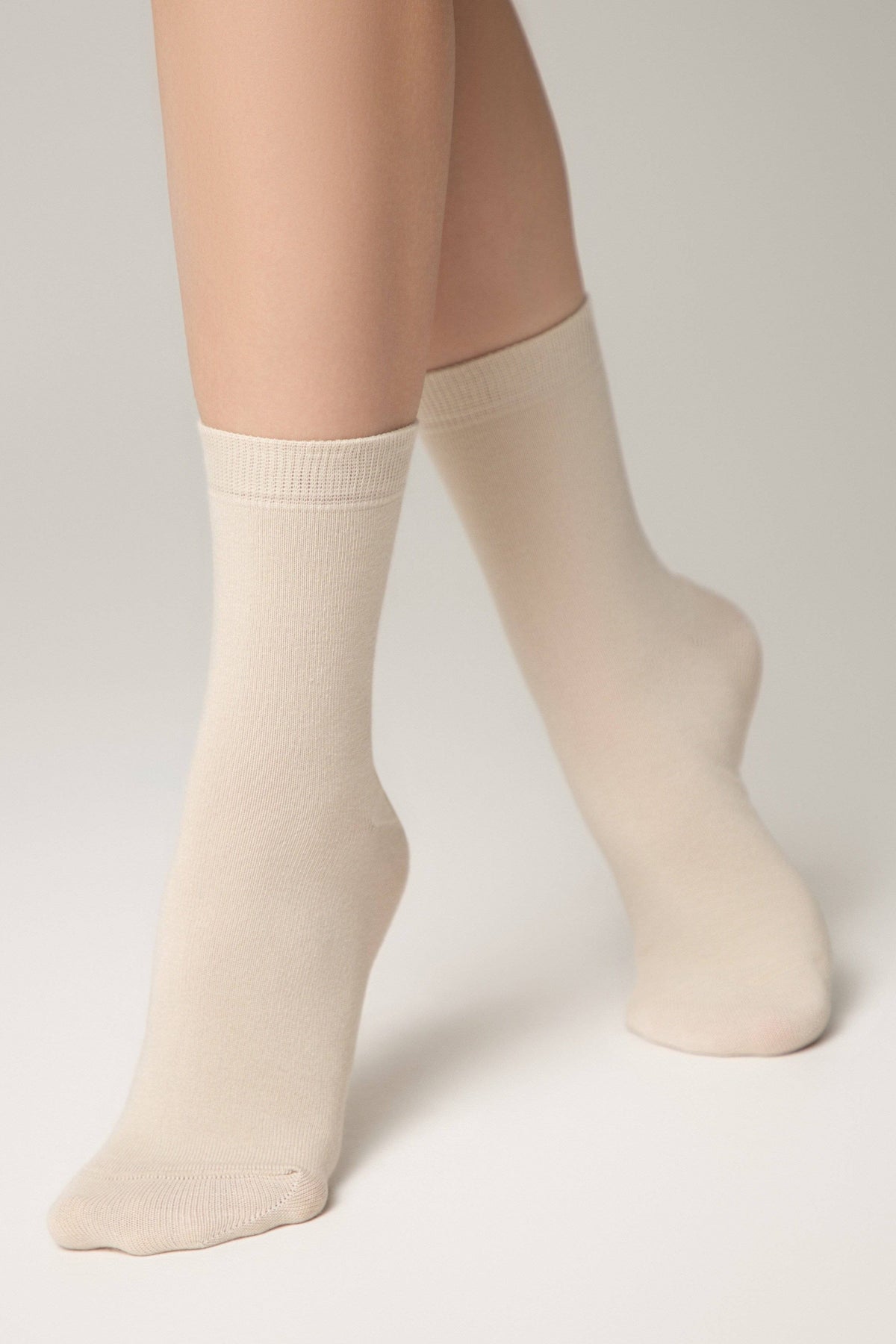 Beige crew socks worn on a person's feet against a light background.