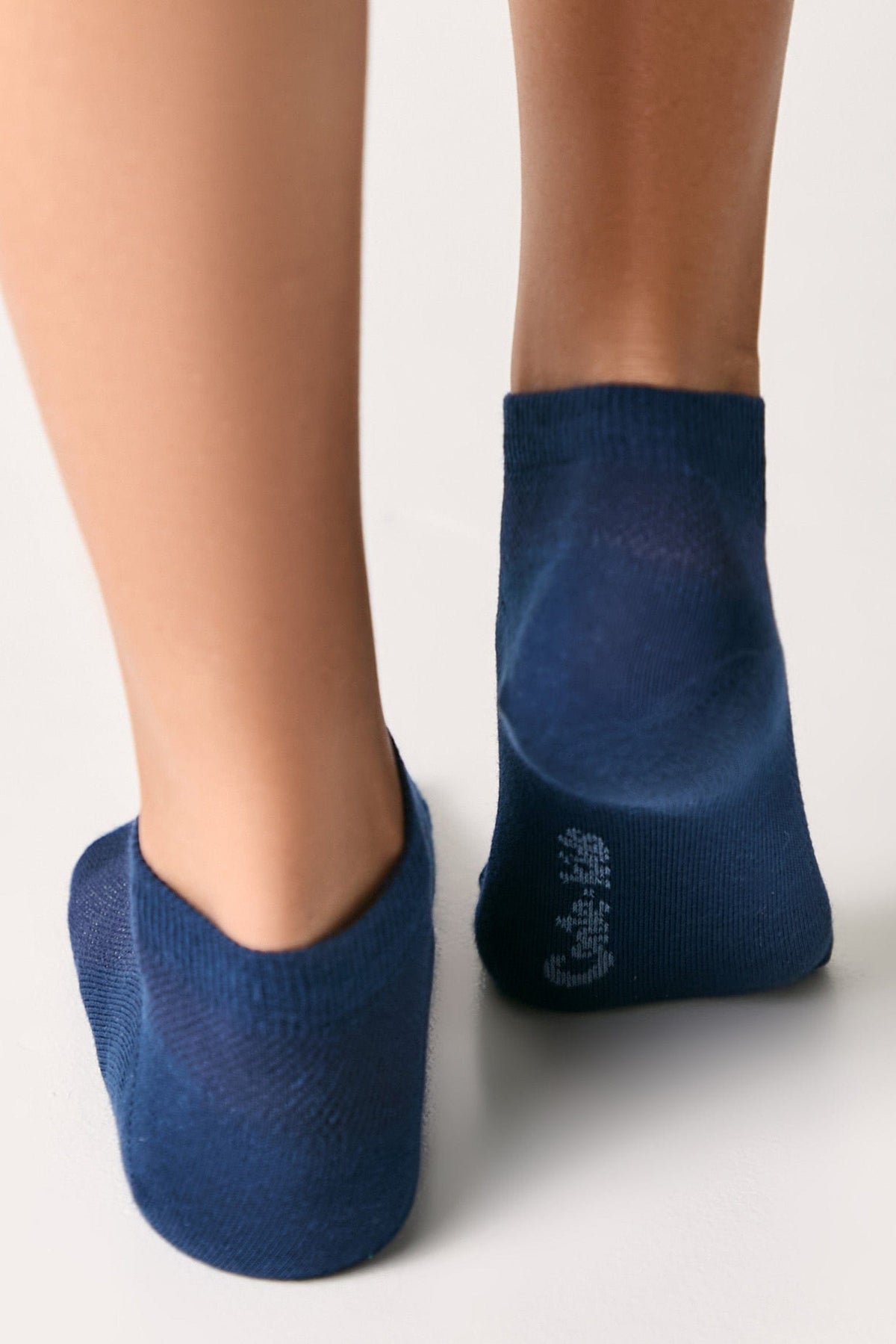 A pair of low-cut navy blue ankle socks worn on feet, viewed from behind against a plain white background.