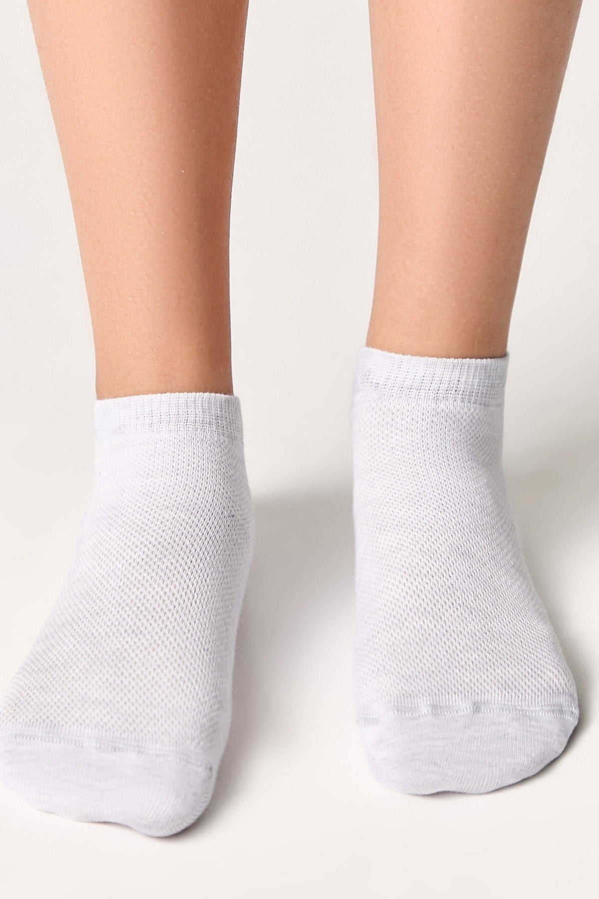 A pair of plain white ankle socks worn on feet against a simple light background.