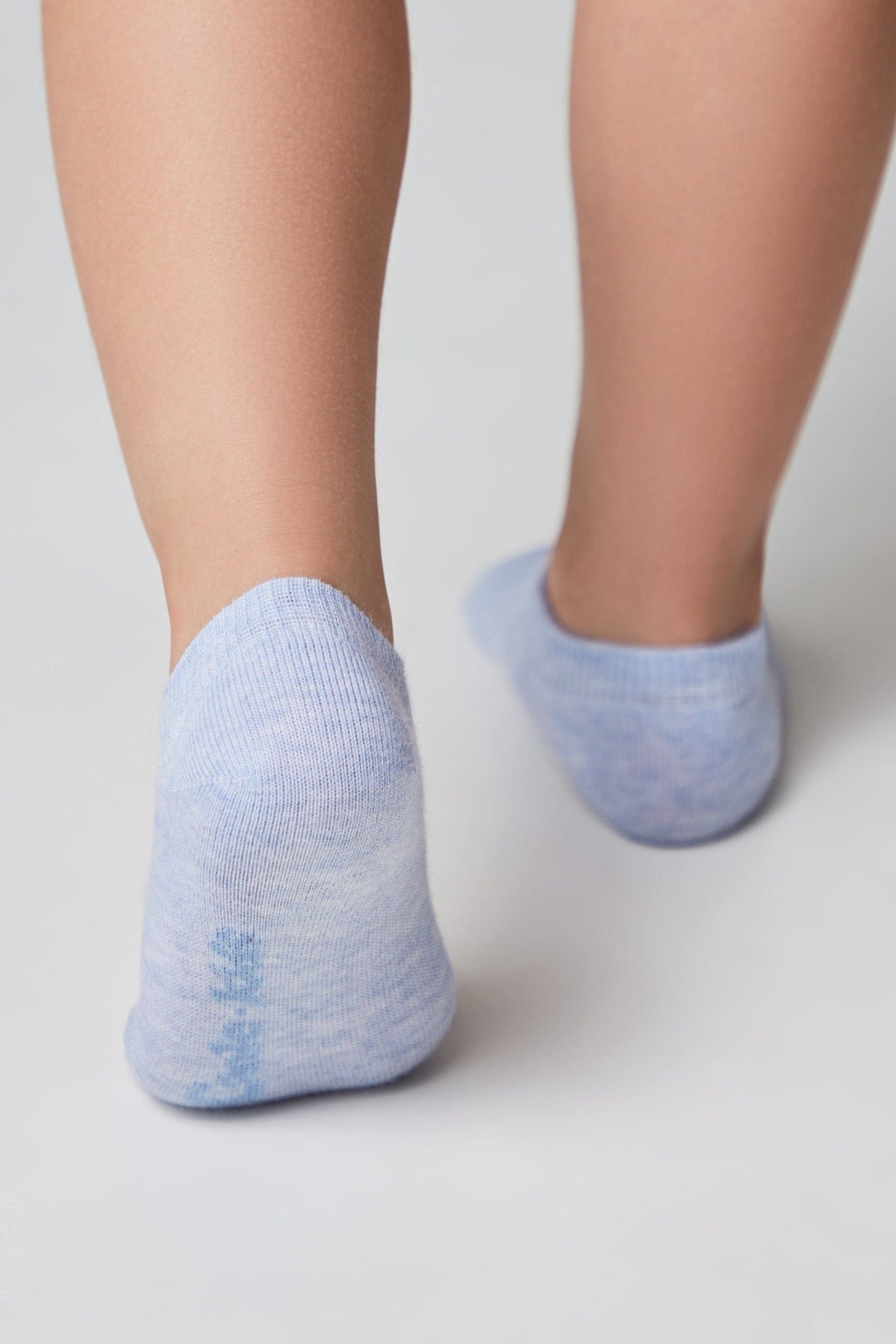 A pair of light blue, marled ankle socks worn on the back of bare feet against a plain white background.