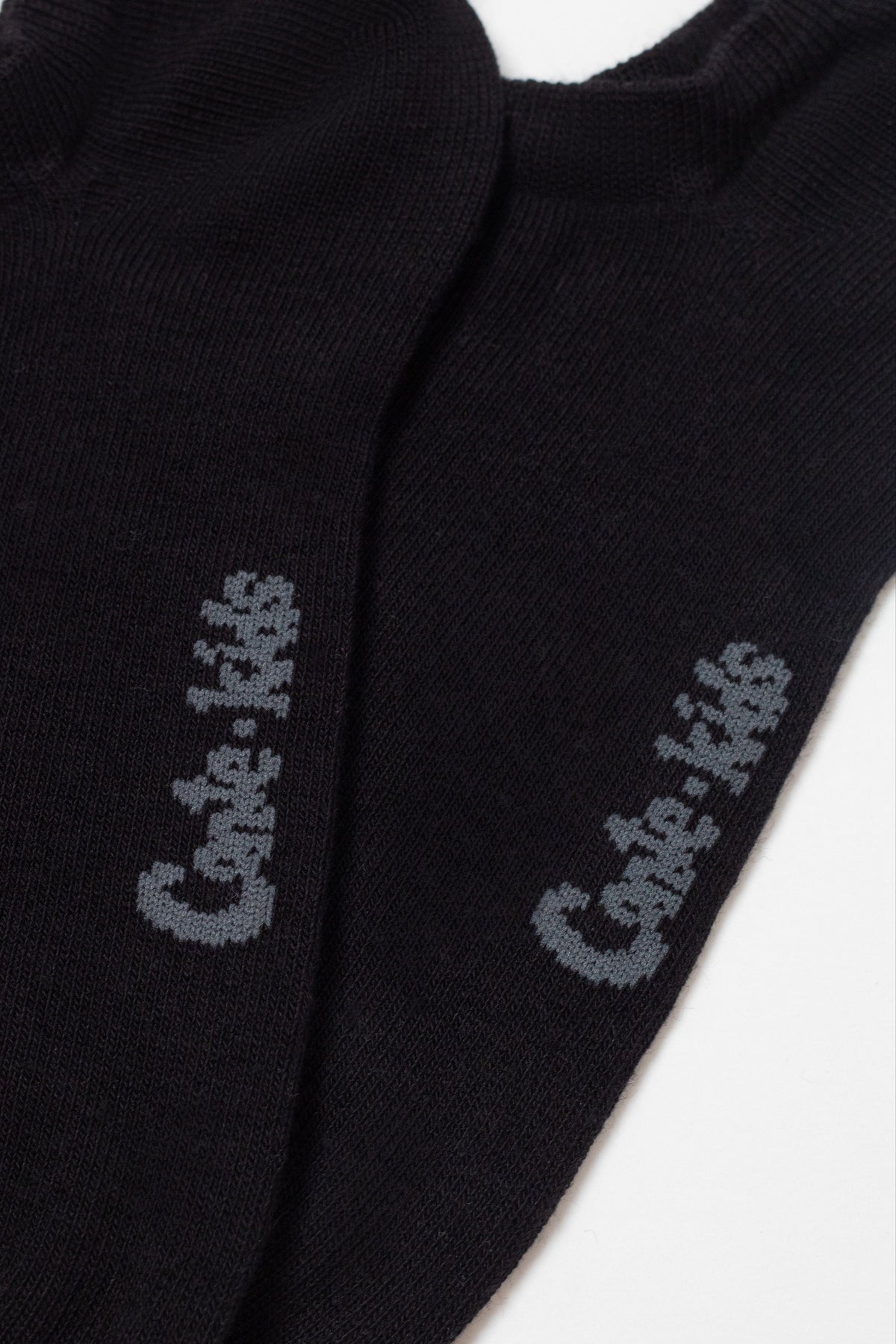 A pair of black ankle socks featuring the grey stitched text conte-kids on each side.