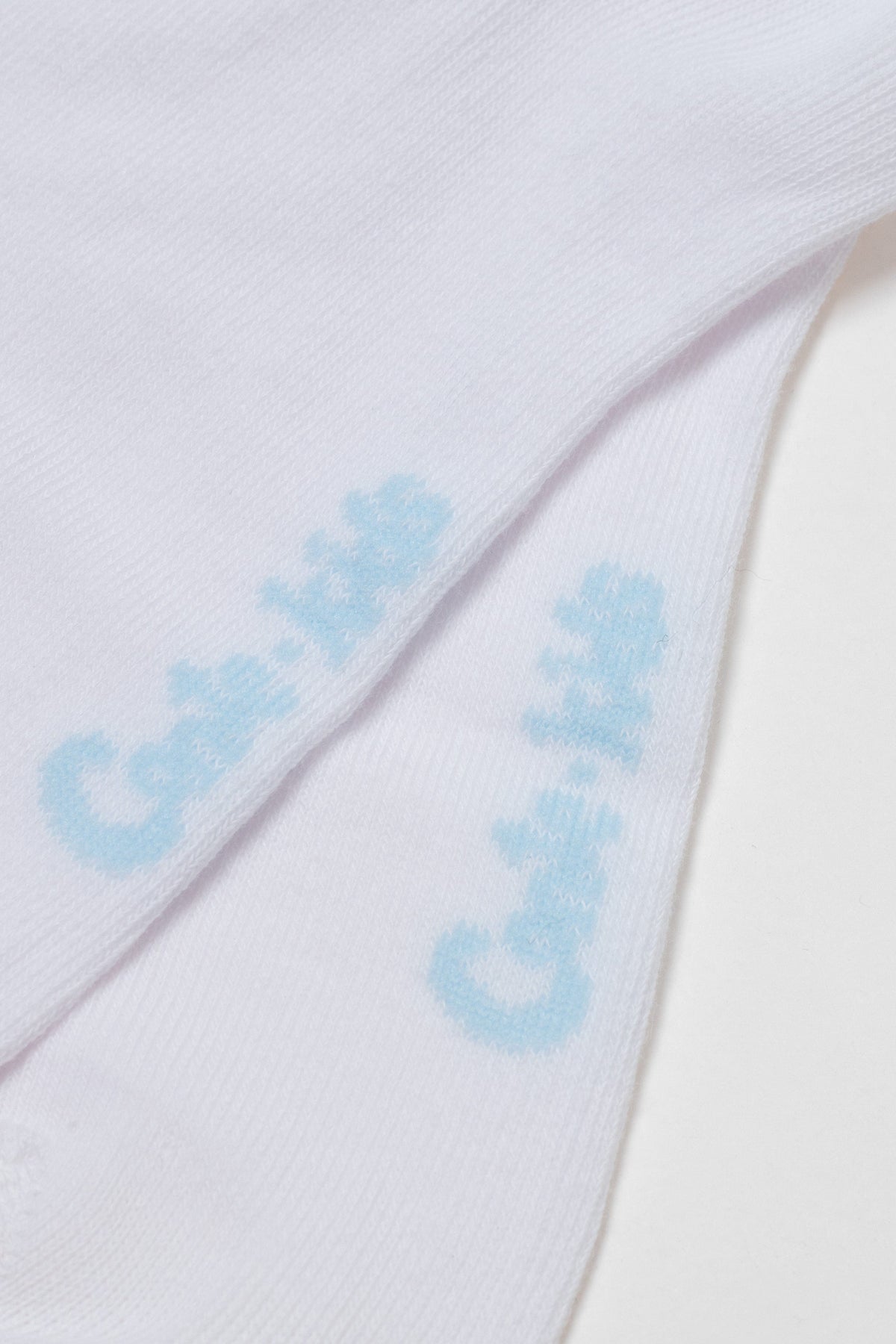 Two folded white socks feature the light blue logo print Cat & Jack on the upper side of each sock.