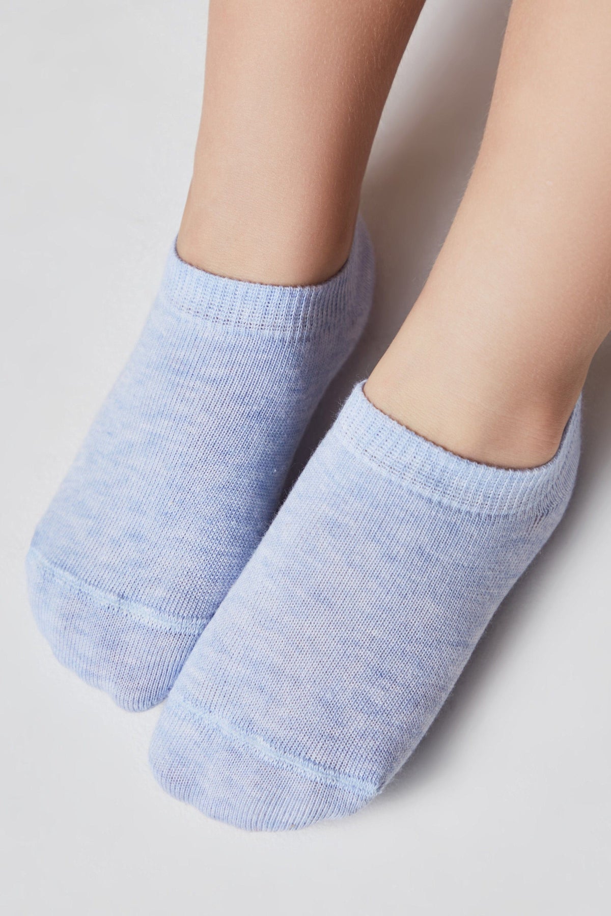 A pair of light blue ankle socks worn on feet against a plain white background.