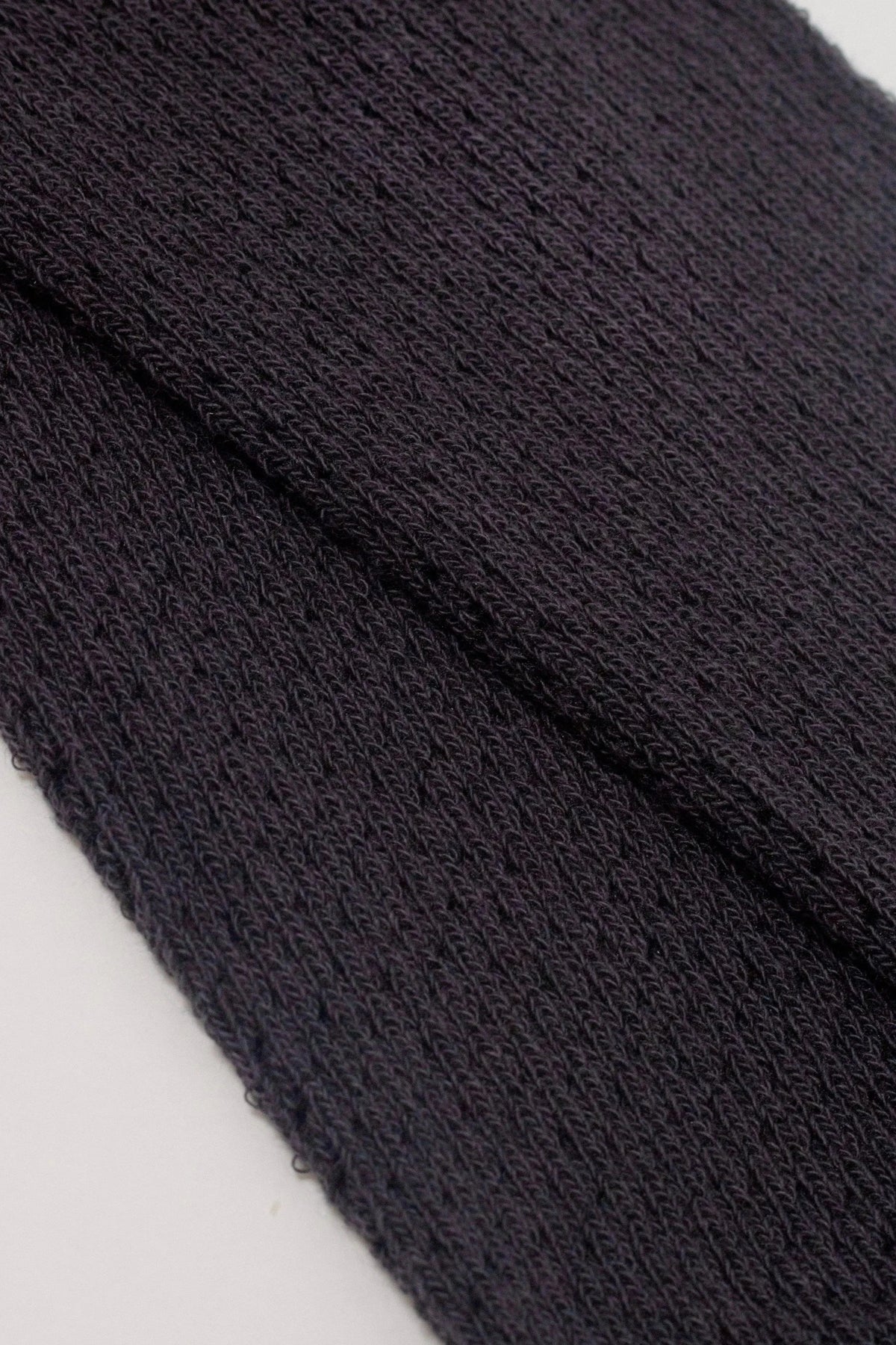 A close-up view of dark purple fabric with a visible knitted or textured weave pattern.