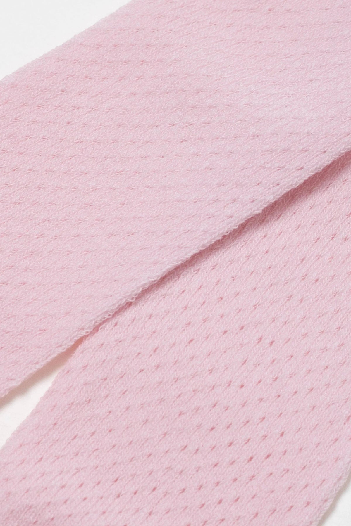 Light pink knit fabric featuring a repeating diamond-shaped perforated pattern.