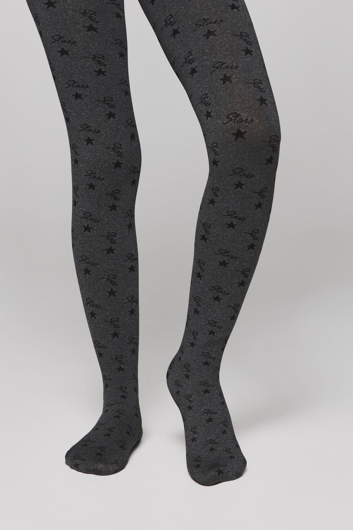 A pair of dark grey glittery tights patterned with black stars and the cursive word stars set against a plain light background.