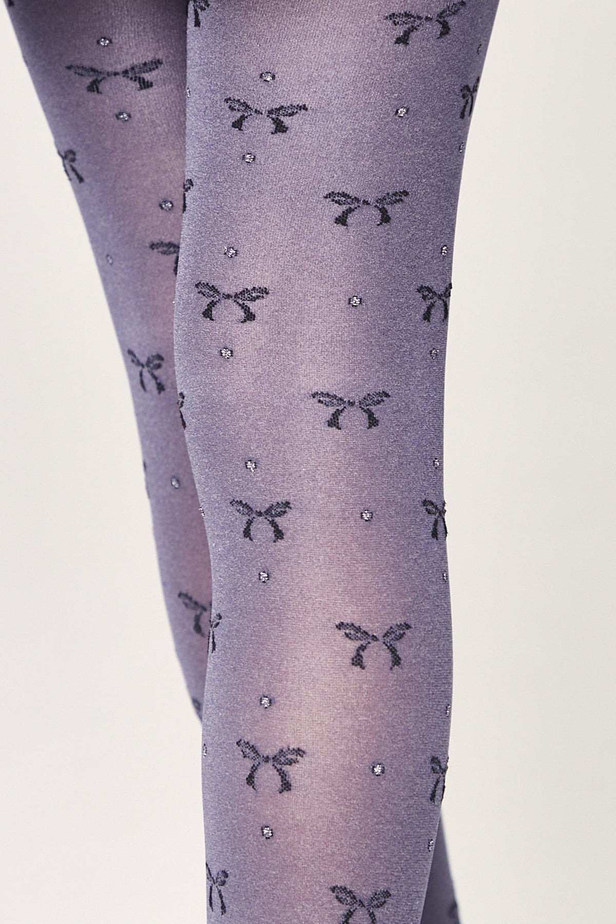 Grey tights featuring a repeating pattern of small black bows and tiny silver shimmering dots.