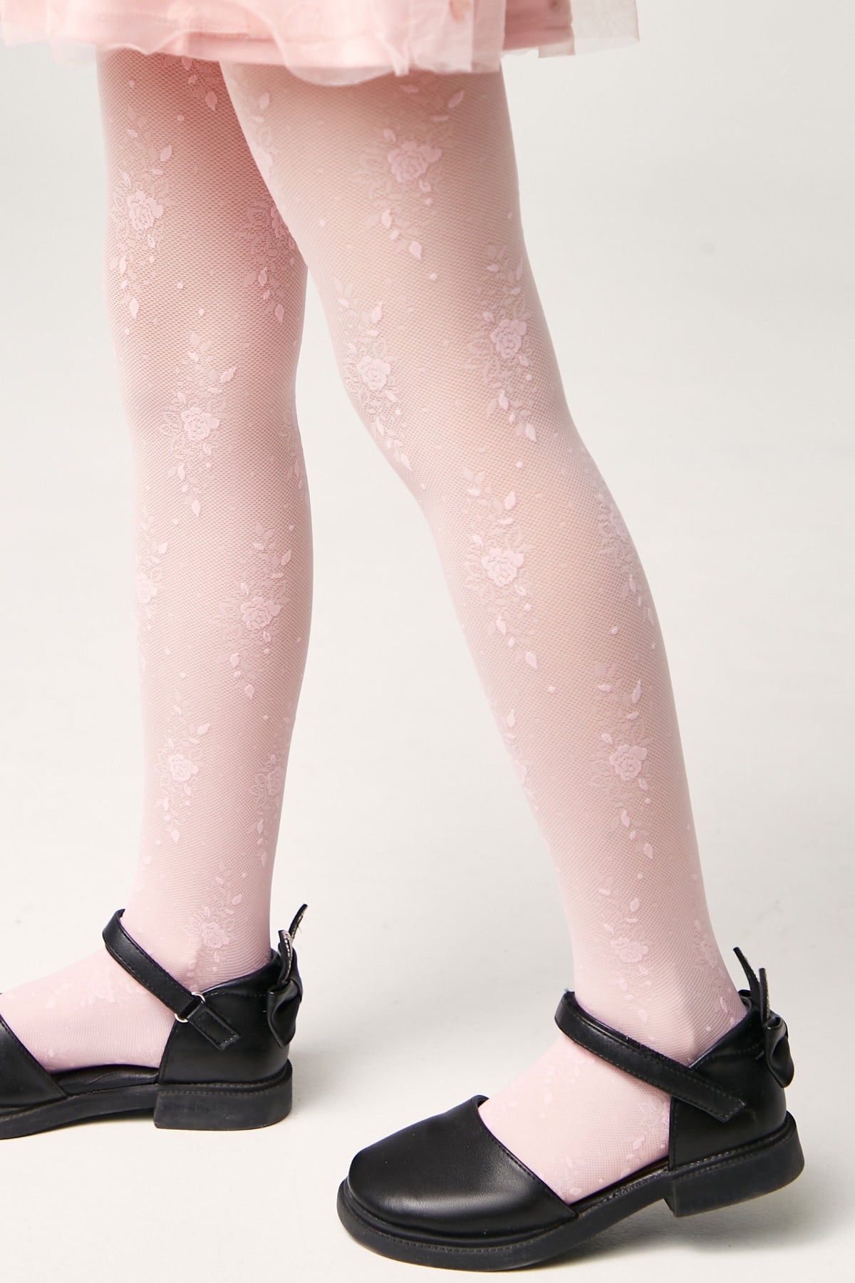 Light pink floral patterned tights worn with black Mary Jane shoes.