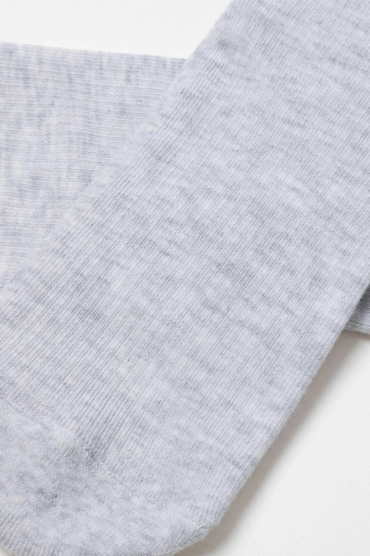 A close-up of a light grey heathered knit sock featuring a visible vertical ribbed texture.