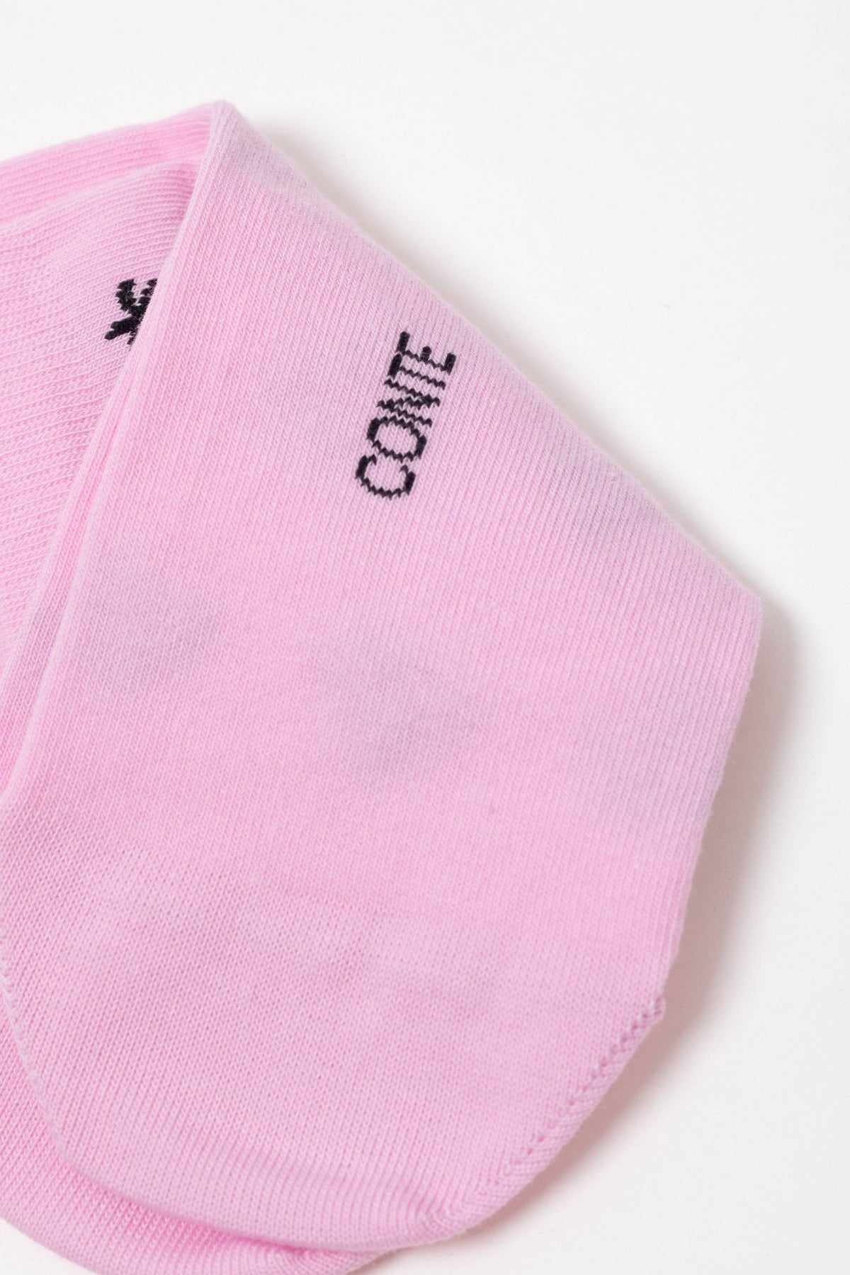 A close-up view of a light pink sock featuring the word CONTE stitched in black thread near the top edge.