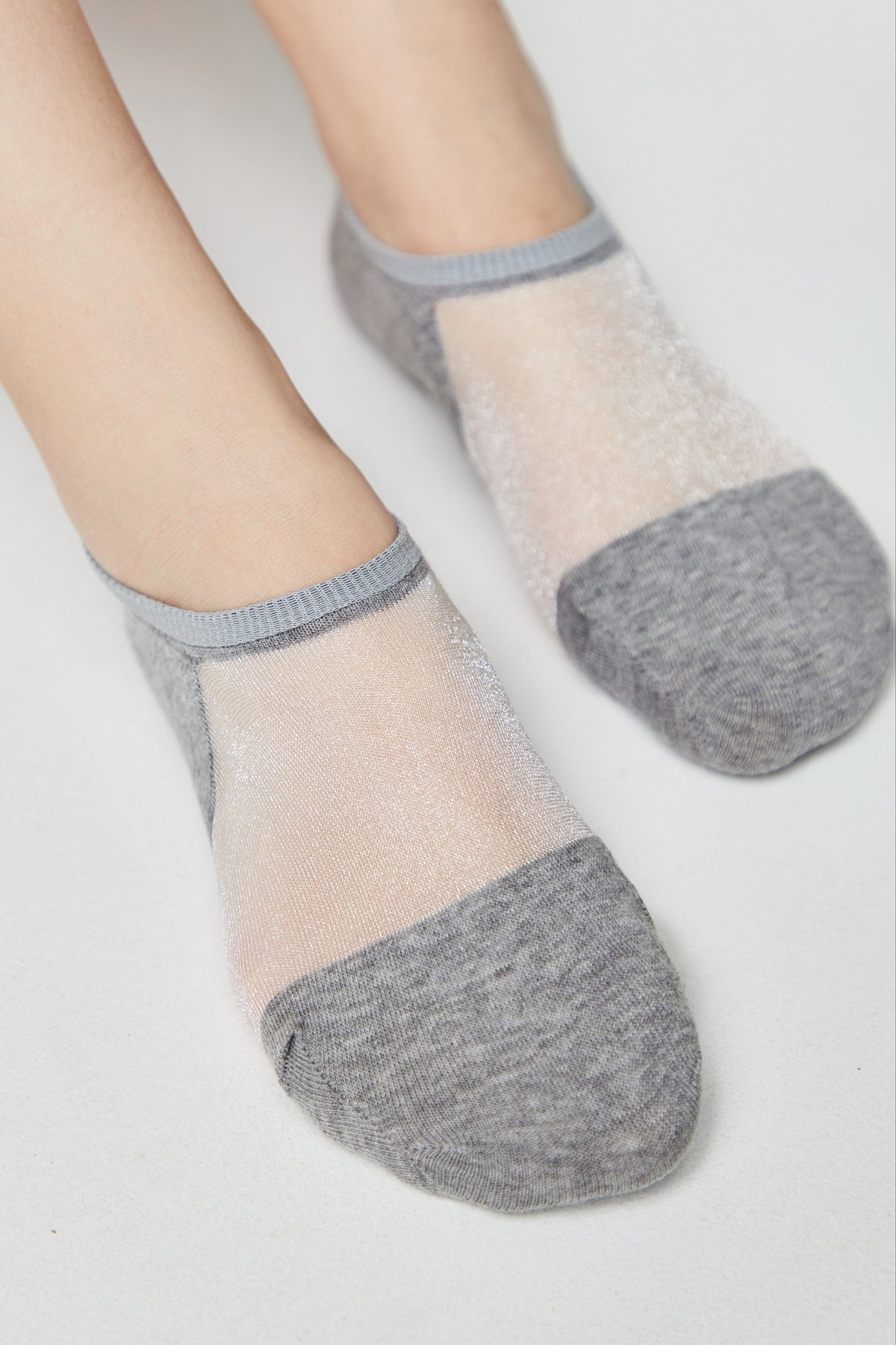 A pair of grey low-cut socks featuring a sheer, shimmering mesh panel across the top of the foot.