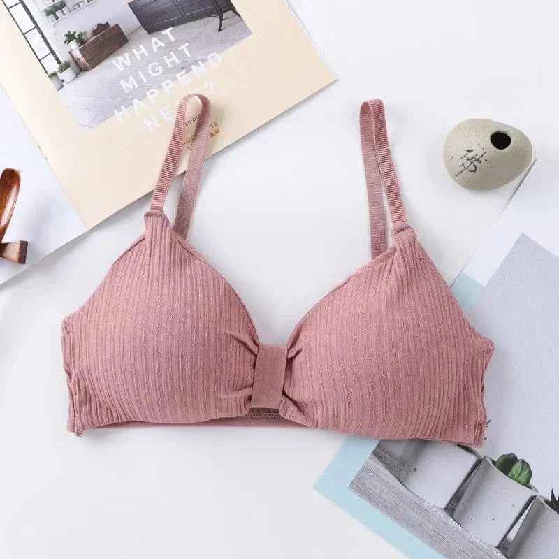 A mauve-colored ribbed bralette with thin shoulder straps and a simple center knot detail, displayed on a flat surface with decorative paper backgrounds.