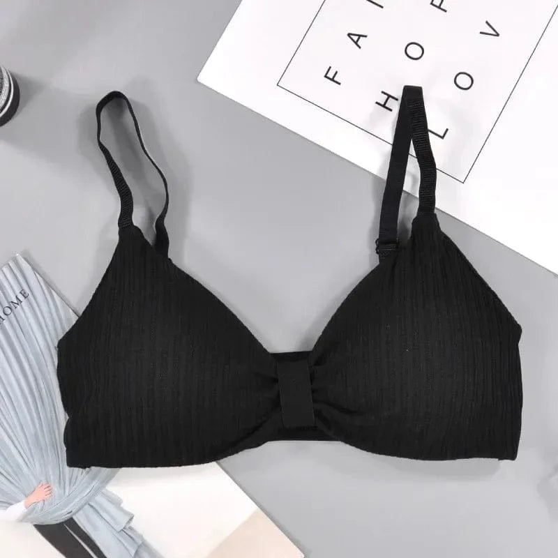 A black ribbed bralette with thin adjustable straps and a center tab detail laying on a grey background.