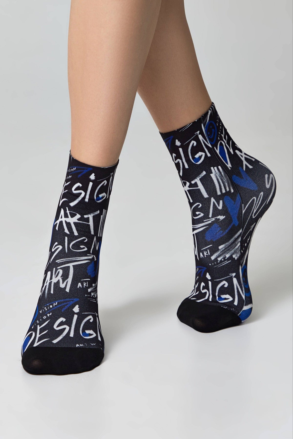 A pair of black crew socks with a repeating white and blue graffiti-style print featuring the words design and art.