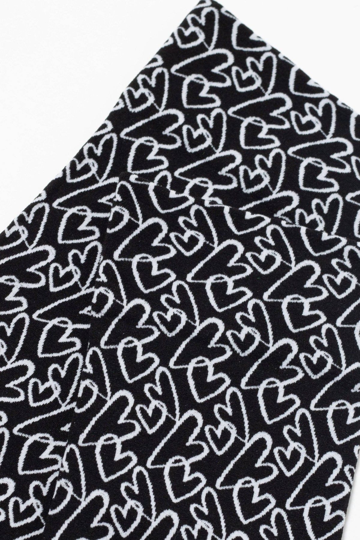 A close-up view of a black fabric featuring a repeating white hand-drawn heart pattern.