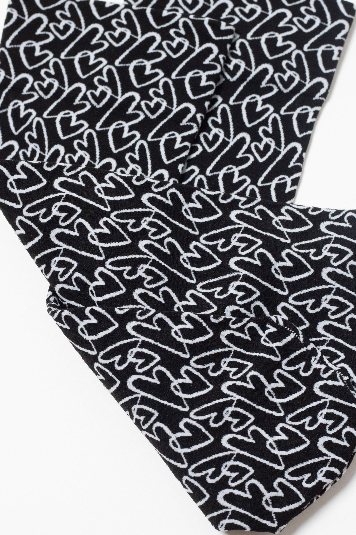 Close-up view of black fabric featuring an all-over repeating white hand-drawn heart pattern.