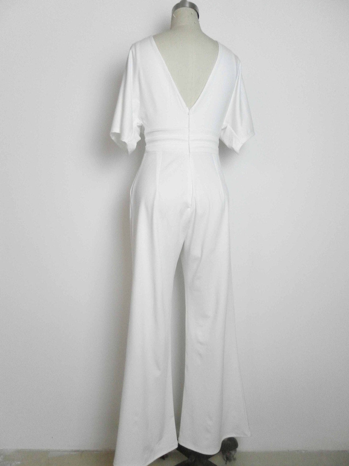 A white short-sleeved jumpsuit on a mannequin, featuring a deep V-neckline on the back and wide-leg trousers.