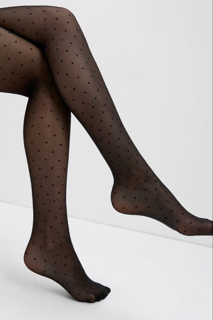 Sheer black tights patterned with small, evenly spaced dark dots worn on legs against a plain white background.