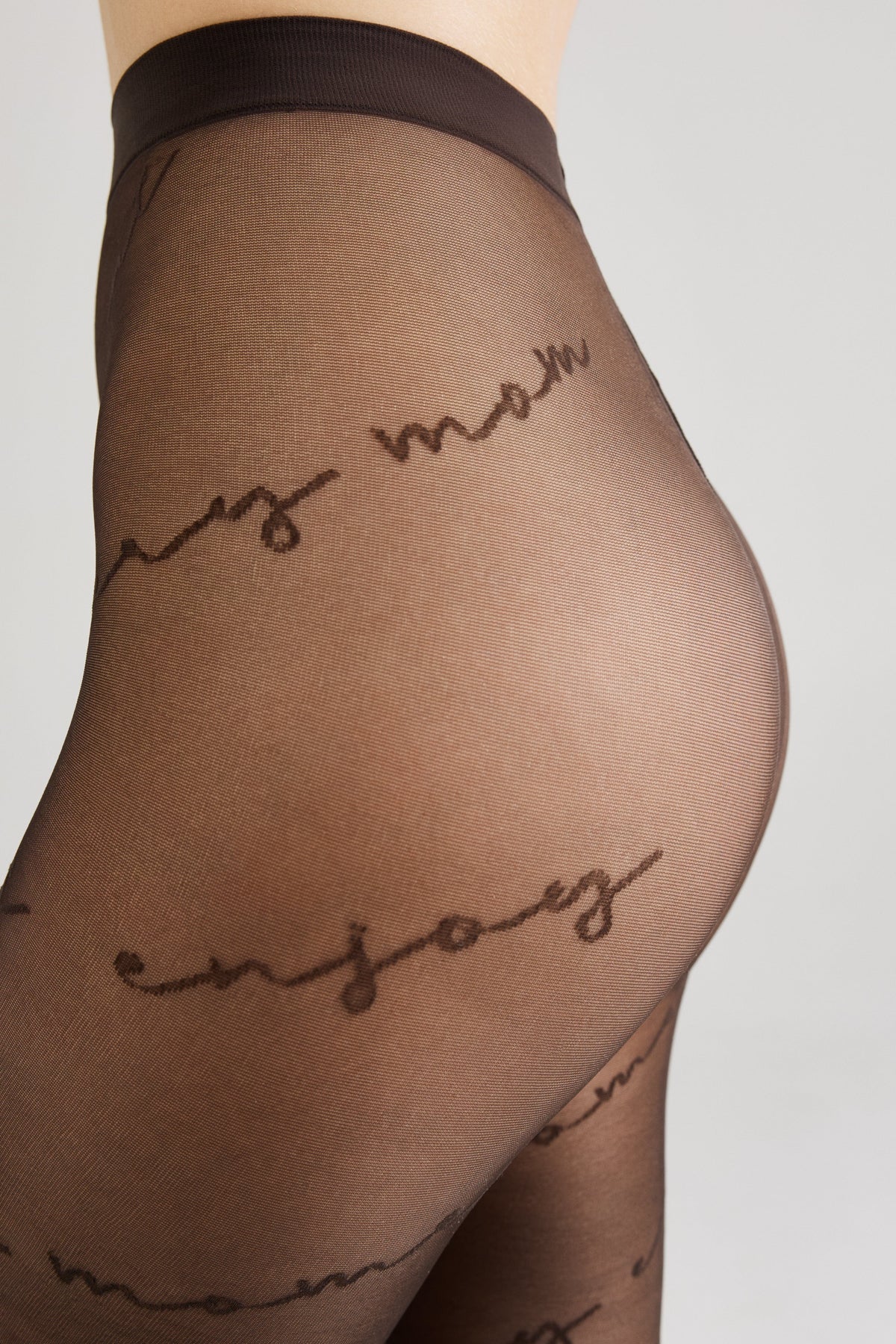 A close-up side profile of a person wearing sheer brown tights patterned with repeating cursive script text.