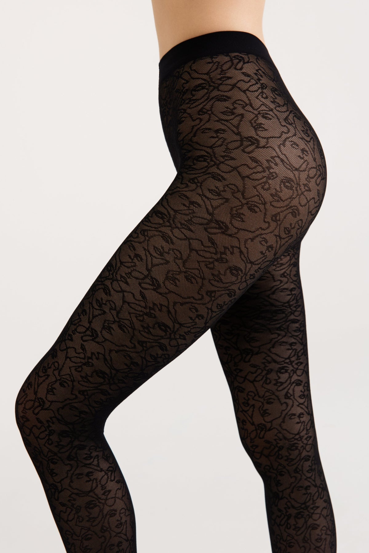 Black patterned tights featuring a repeating line art face design worn on a person's legs against a plain white background.