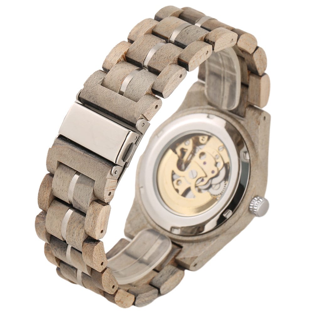 A wooden link bracelet watch is shown from the back, revealing the exposed mechanical movement through the transparent case back and a metallic deployment clasp.