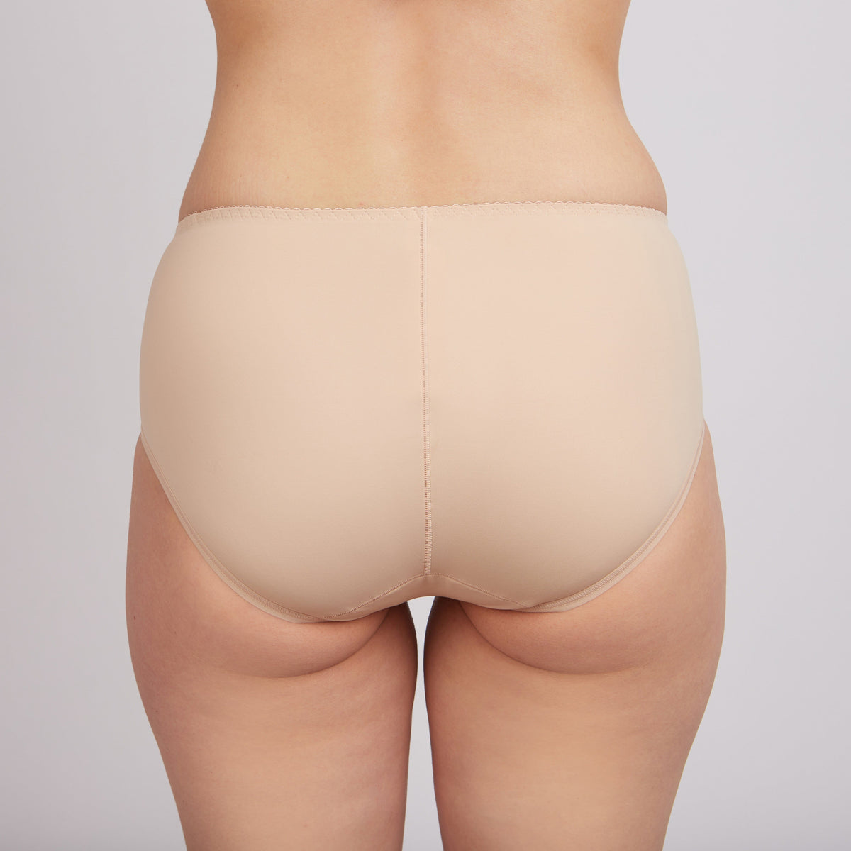 A back view of a pair of beige, full-coverage briefs worn on a person against a neutral background.