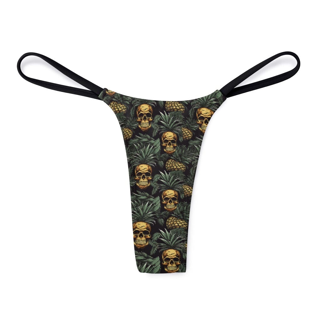 A thong featuring a repeating pattern of skulls nestled inside pineapples against a dark tropical leaf background with thin black side straps.