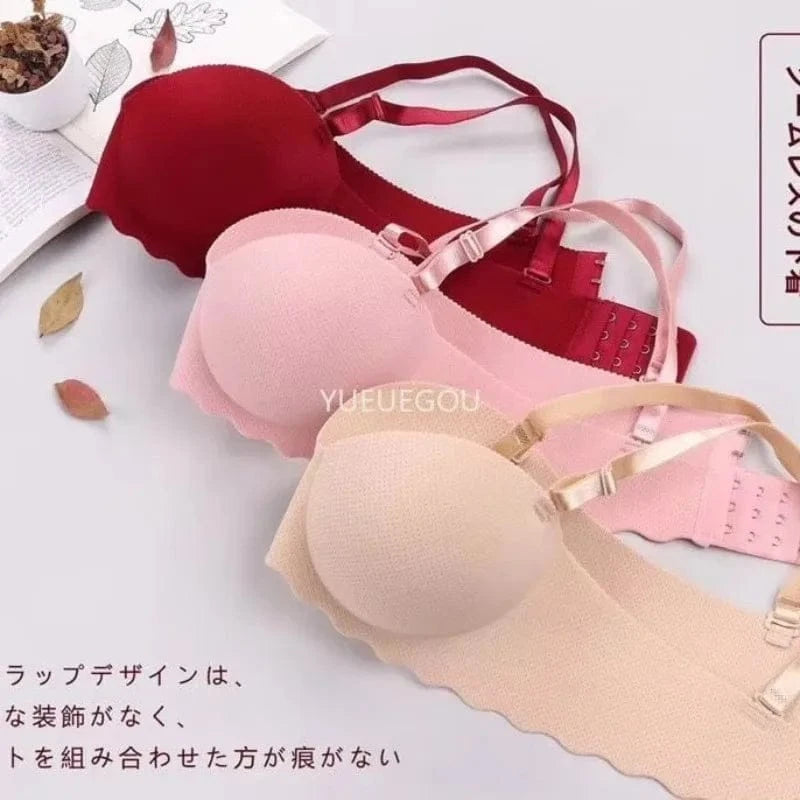 Three strapless bras in maroon, light pink, and beige are stacked vertically against a white background, featuring scalloped edges and adjustable straps.