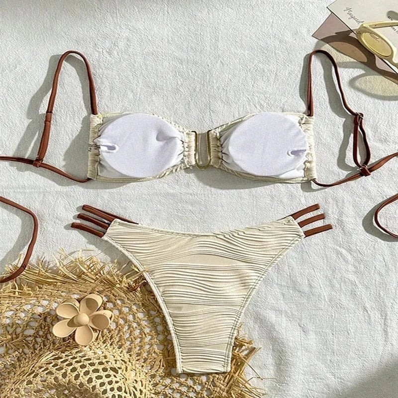 A beige two-piece bikini set with a textured rippled fabric, featuring a strapless top with removable pads, brown adjustable spaghetti straps, and matching high-cut bikini bottoms with triple side-strap details.