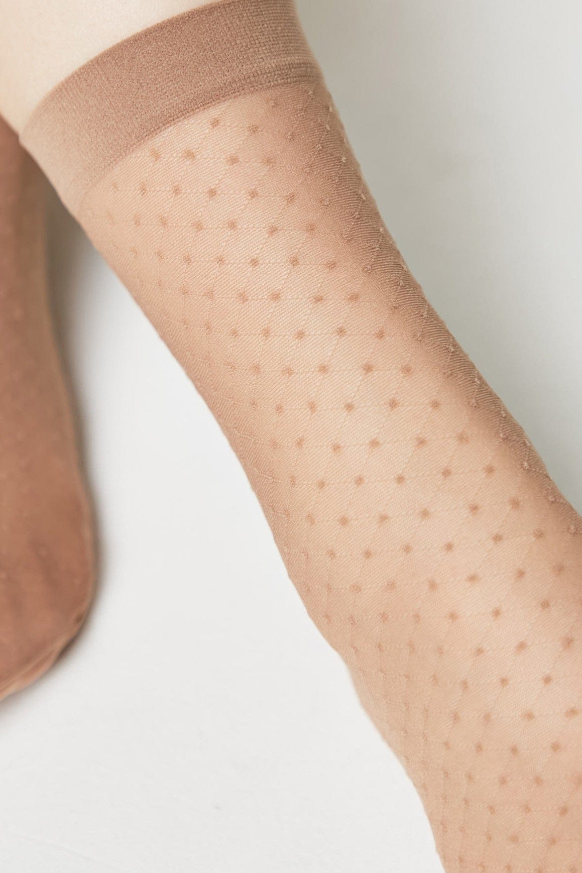 Beige sheer ankle socks with a repeating diamond dot pattern and an elasticated band at the top.