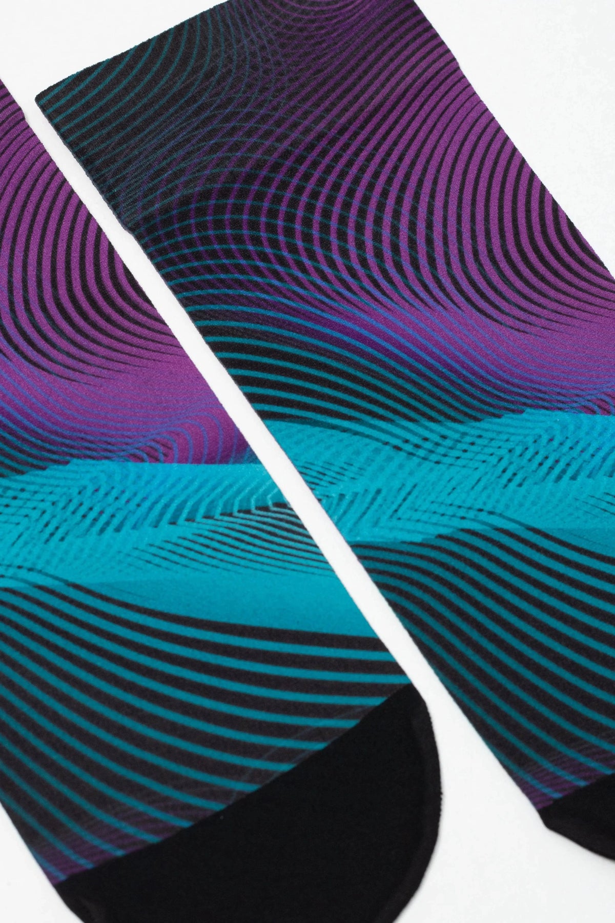 A pair of crew socks featuring a vibrant, abstract wavy pattern that transitions from deep purple at the top to a bright teal in the middle, finished with solid black toe and heel sections.