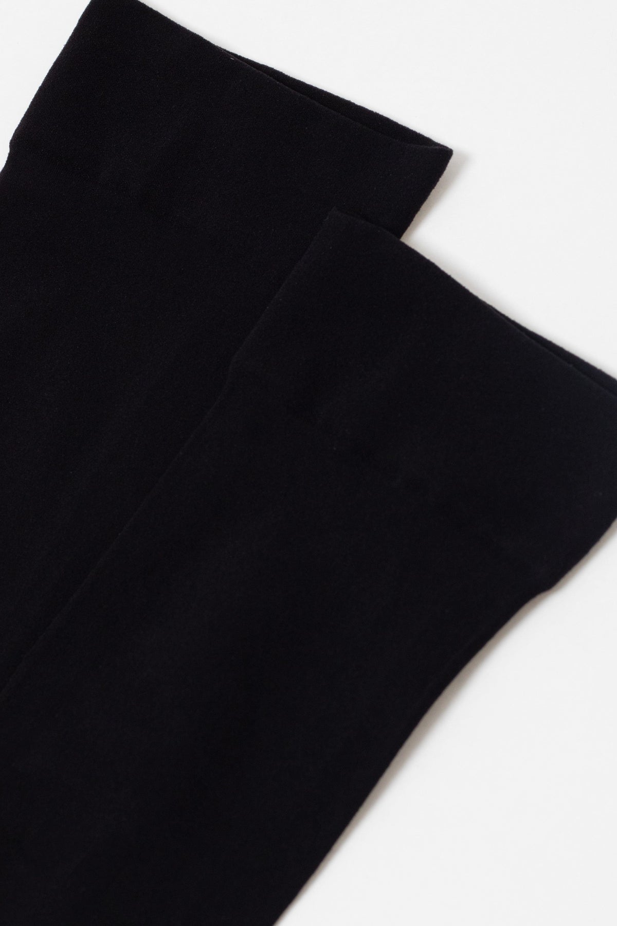 A pair of plain black socks shown against a solid white background.