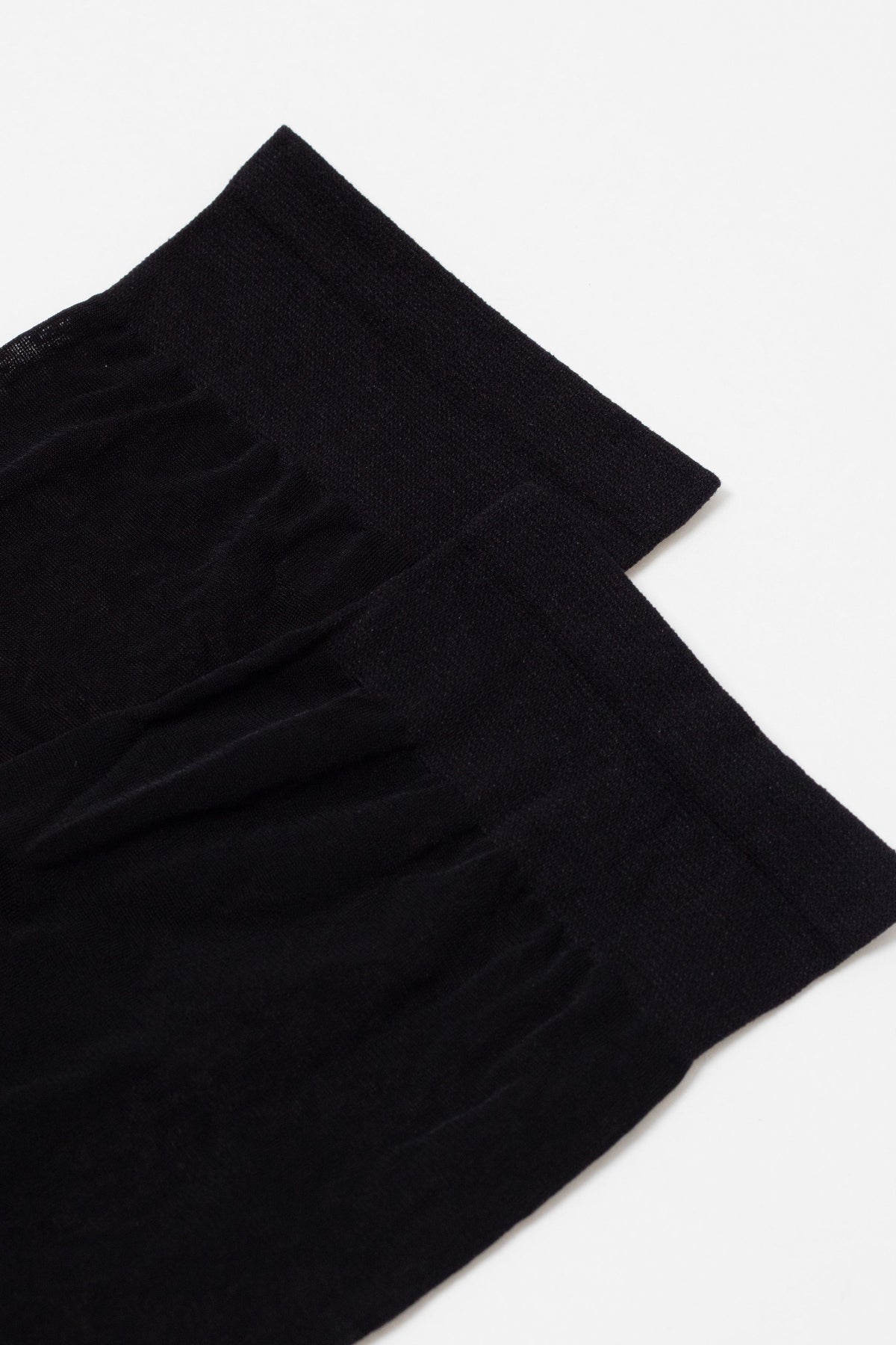 Two black socks shown from the top down, featuring ribbed cuffs and a smooth, fine-knit fabric texture on a plain white background.