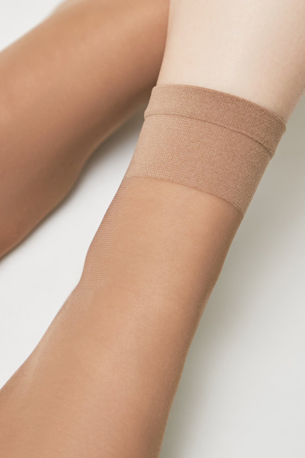 Nude-colored hosiery covering a person's lower legs against a plain white background.