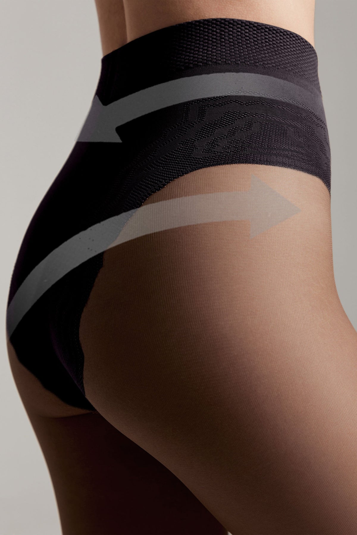 A close-up of dark grey high-waisted shaping pantyhose featuring a textured waistband and a sheer panel across the hip with superimposed light grey directional arrows.