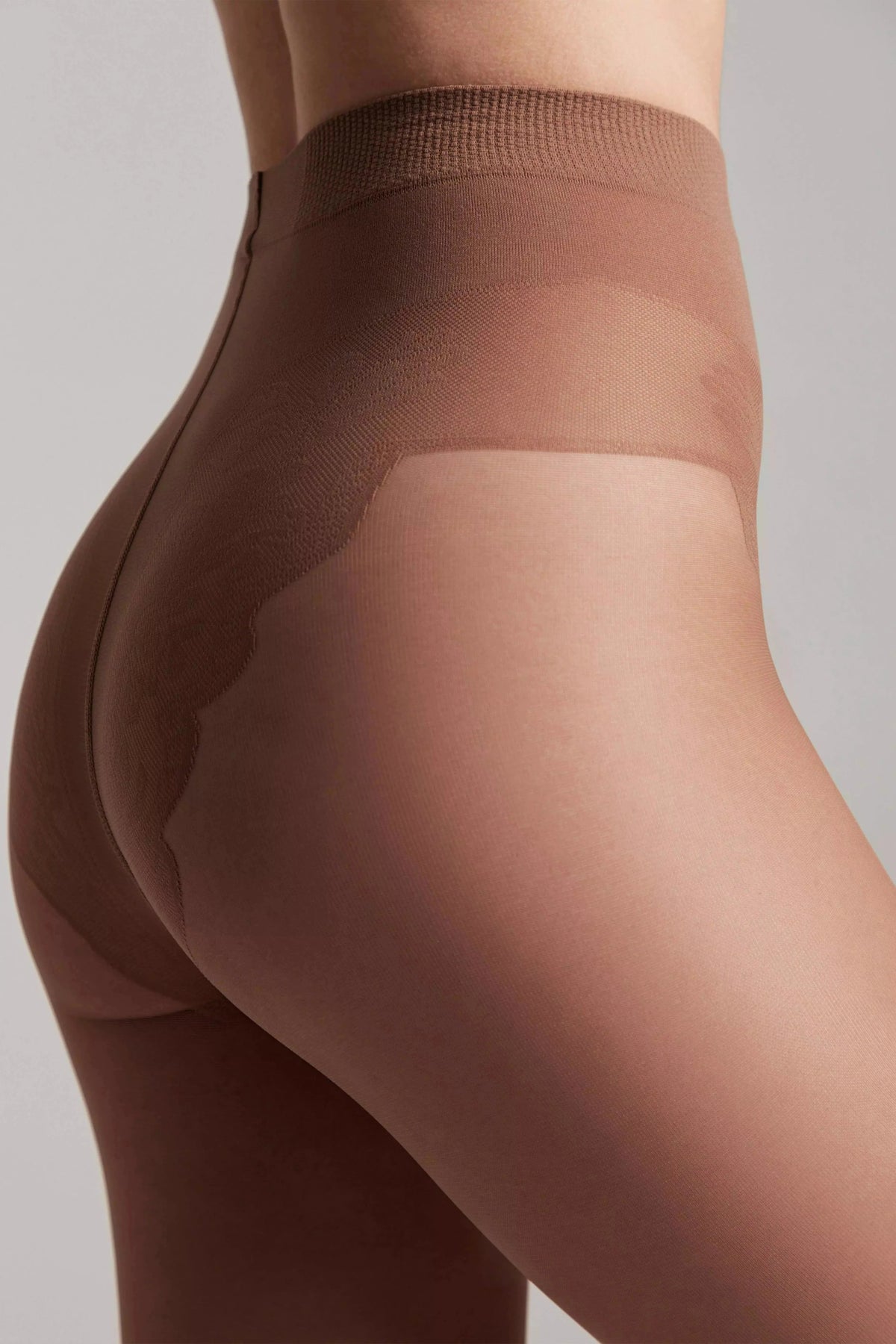 Tan pantyhose worn on a person, featuring a reinforced shaping brief with a distinct lace-like pattern along the hips and rear.