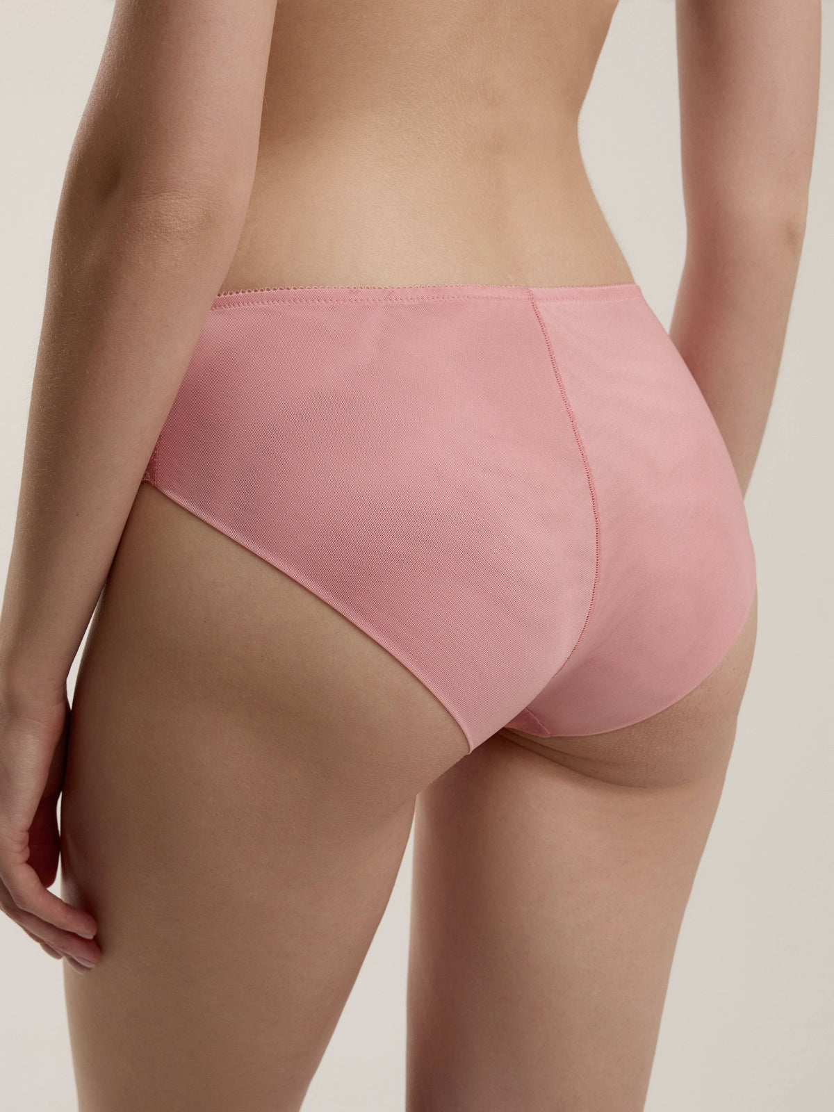 A pair of pink bikini-style panties viewed from behind on a person against a plain background.