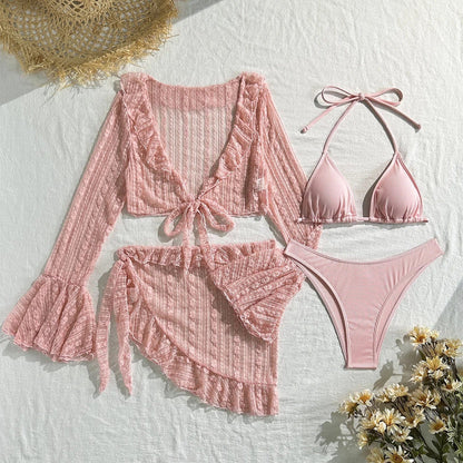 A light pink three-piece bikini set consisting of a ribbed triangle bikini top and high-cut bottoms, accompanied by a matching sheer, long-sleeved, ruffled tie-front cover-up and a ruffled wrap skirt.