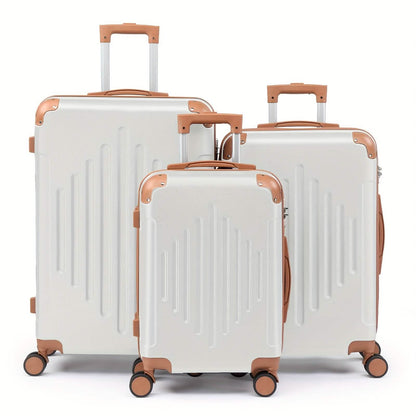 Three light silver suitcases of varying sizes stand in a row, each featuring brown corner protectors, handles, and wheels against a white background.