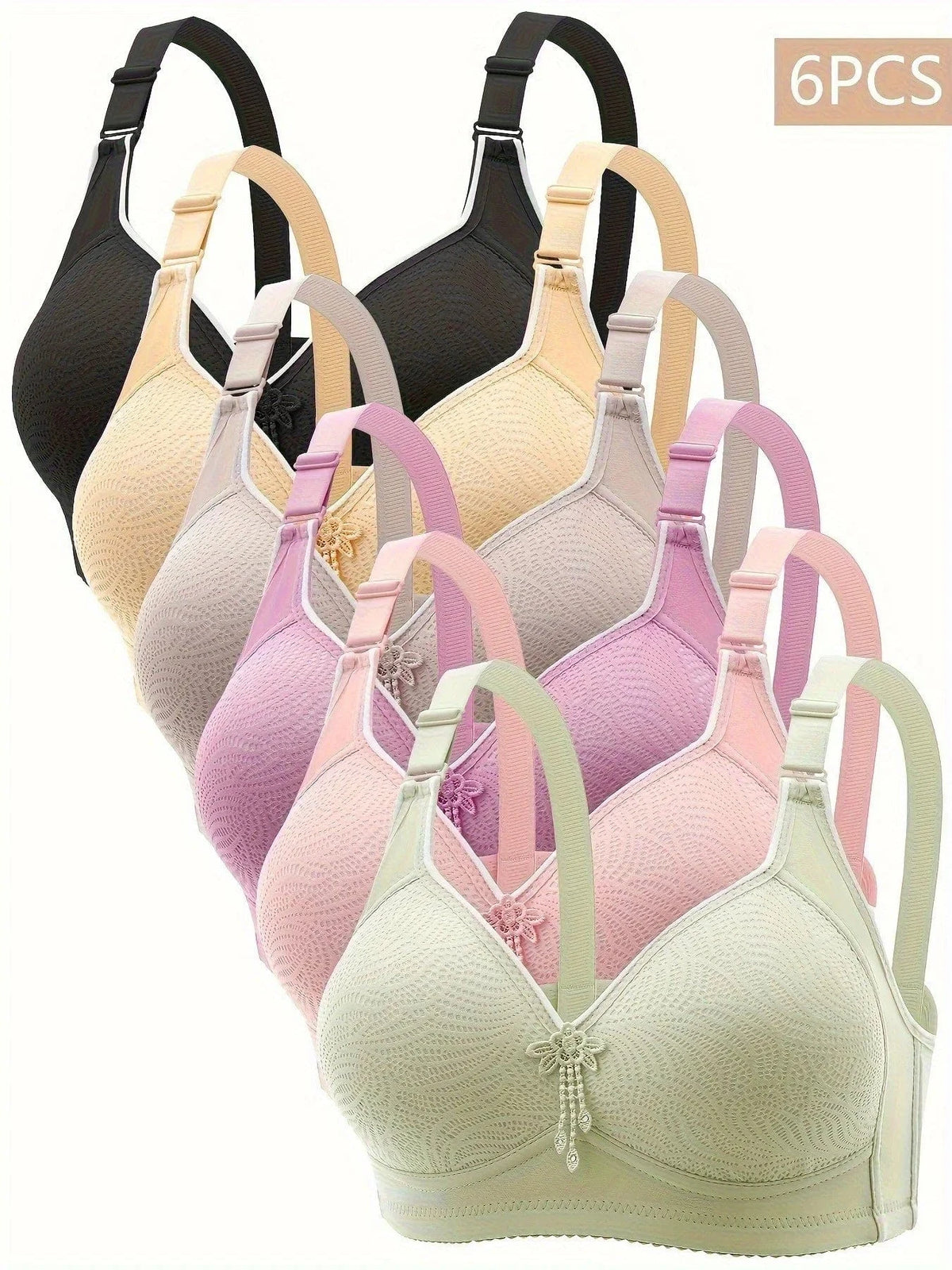 Six wireless bras with textured fabric and small decorative floral charms, displayed in a stacked arrangement featuring black, beige, lavender, pink, and light green colors.