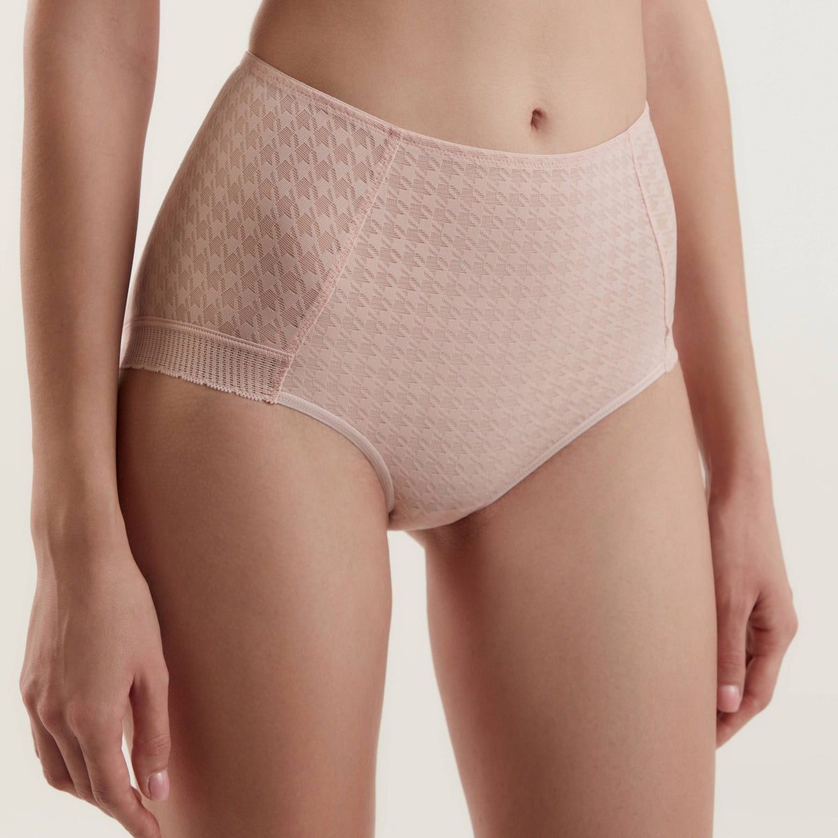 High-waisted, light pink panties featuring a subtle houndstooth pattern on the side panels and a solid center panel worn by a person.